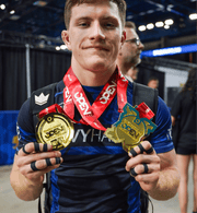 Heavy Handed athlete wearing Combat Division Blue rashguard showing medals won at a tournament. 